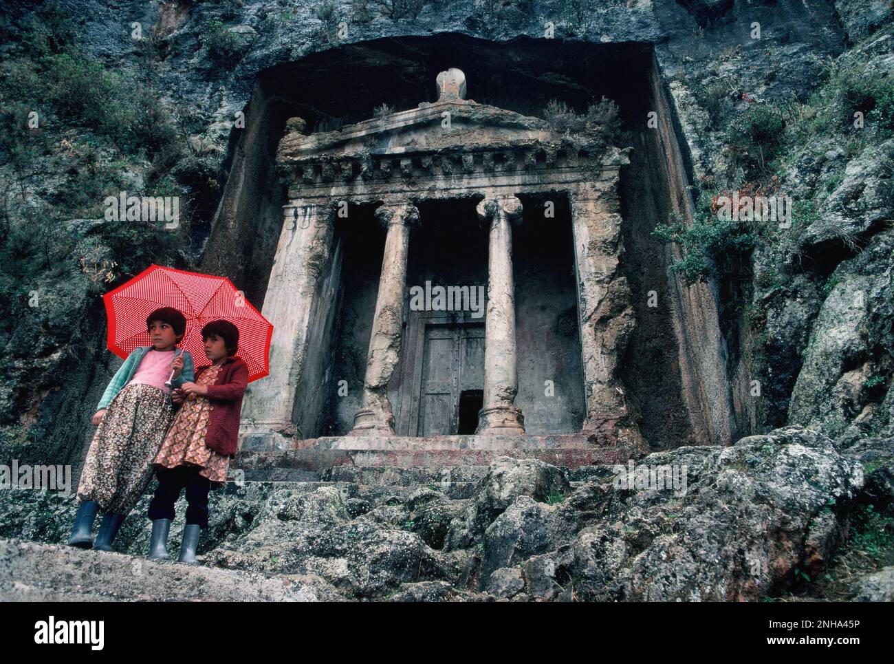 Turquie. Fethiye. Ruines de la tombe d'Amyntas. Deux jeunes filles debout avec un parapluie. Banque D'Images