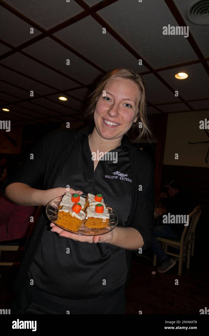 La serveuse souriante sert une assiette de gâteaux d'Halloween décorés de bonbons à la citrouille au restaurant Hilltop sur Sand Lake. Cumberland Wisconsin ÉTATS-Unis Banque D'Images