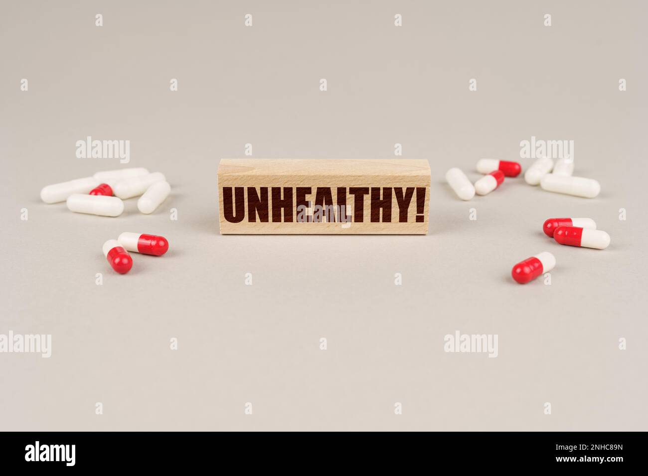 Concept médical. Sur une surface grise sont des comprimés, des capsules et une plaque de bois avec l'inscription - malsain Banque D'Images