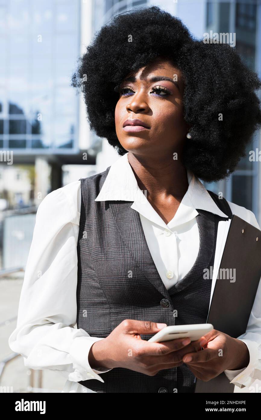 Portrait une jeune femme d'affaires africaine tenant la main du téléphone portable regardant loin Banque D'Images