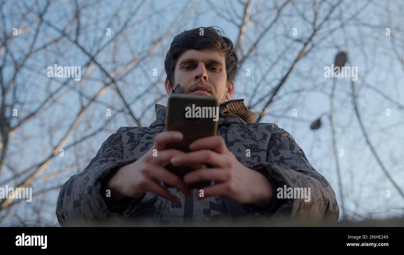 Homme utilisant son smartphone pour la messagerie et les applications, vue de dessous Banque D'Images