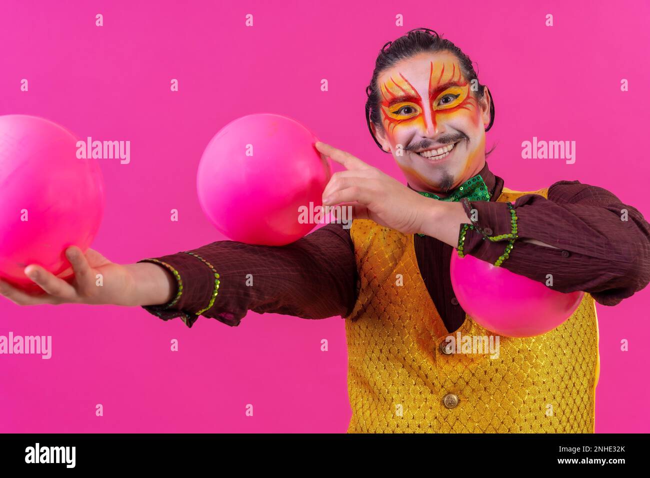 Clown avec maquillage blanc pour le visage sur fond rose, balles de jonglage Banque D'Images