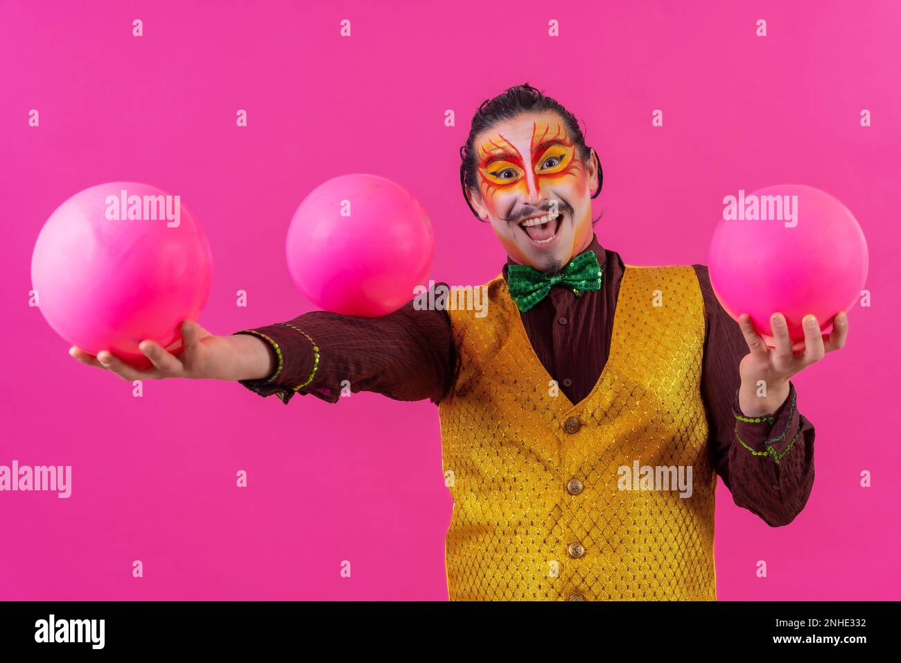 Clown avec maquillage blanc pour le visage sur fond rose, balles de jonglage Banque D'Images
