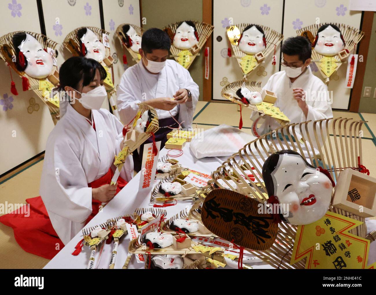 Shrine maidens and priests prepare for Fukuyose, lucky rake with Otafuku masks at Kushida Shrine in Fukuoka City, Fukuoka Prefecture on January 13, 2023, prior to setsubun, the last day of winter in the traditional lunar calendar (usually February 3rd or 4th). Otafuku is a plain-looking woman who invites fortune. The bean-scattering ceremony to drive out devils and attract good fortune has been held in setsubun. ( The Yomiuri Shimbun via AP Images ) Banque D'Images