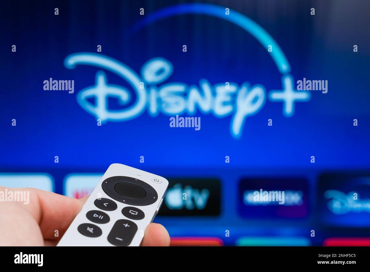 Disney plus sur Apple TV sur l'écran du téléviseur. Homme mains allumer la télévision à l'aide de la télécommande, Fabreary 2023, Prague, République Tchèque. Banque D'Images