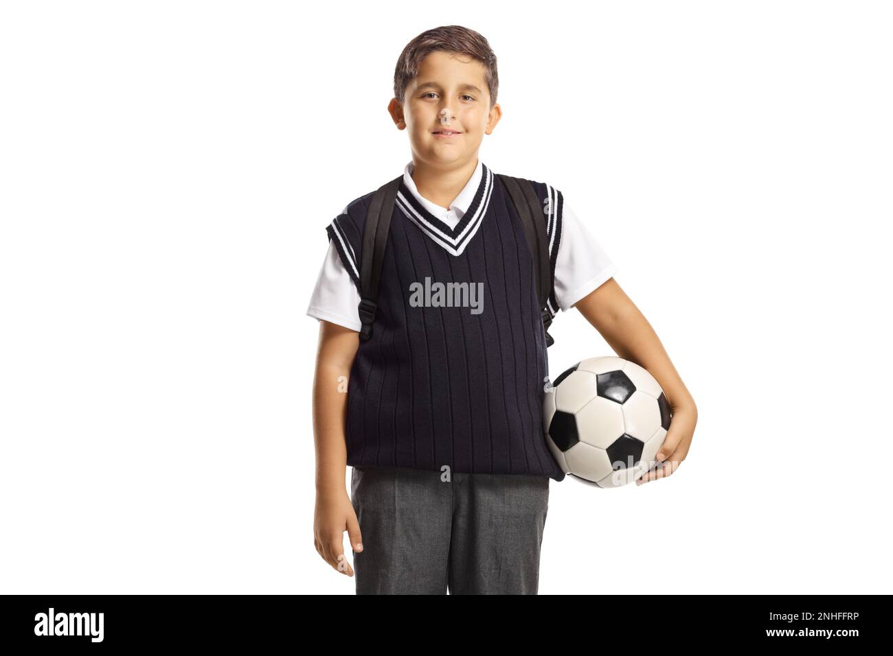 Garçon portant un uniforme scolaire et tenant un ballon de football isolé sur fond blanc Banque D'Images
