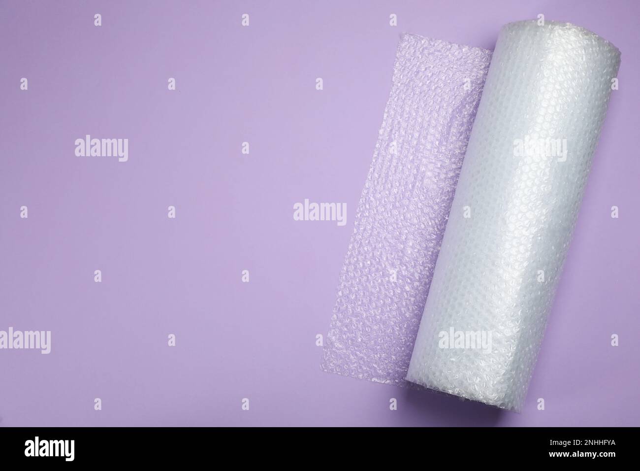 Rouleau d'emballage à bulles sur fond lilas, vue de dessus. Espace pour le texte Banque D'Images