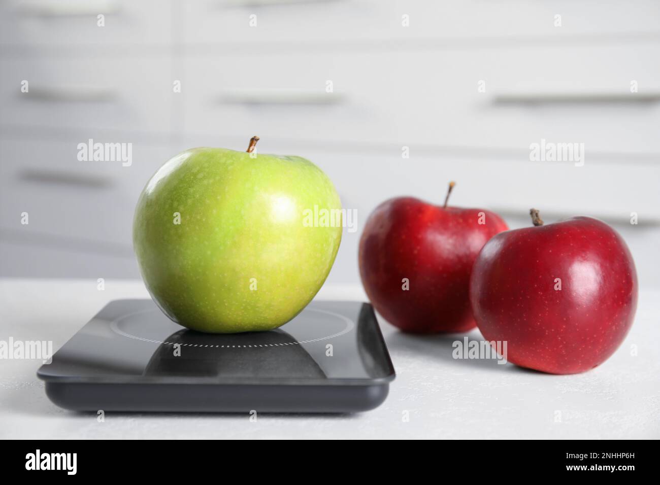 Pommes mûres et balance numérique moderne sur table Banque D'Images