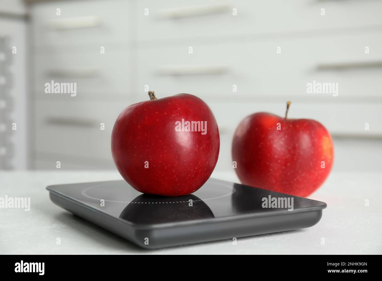 Pommes rouges et balance numérique moderne sur table Banque D'Images