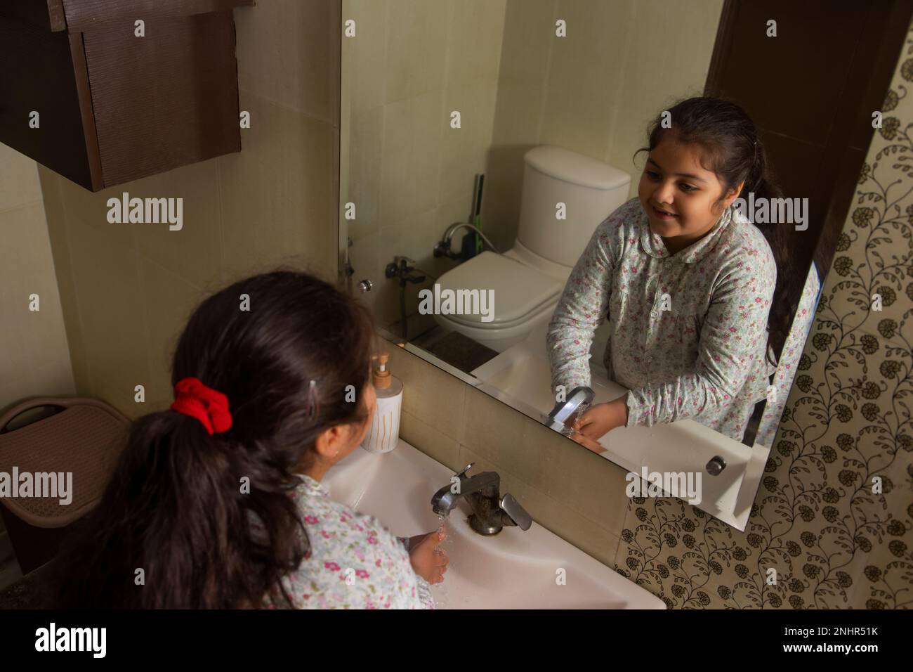 Vue de dessus de la petite fille se lavant les mains dans la salle de bains Banque D'Images