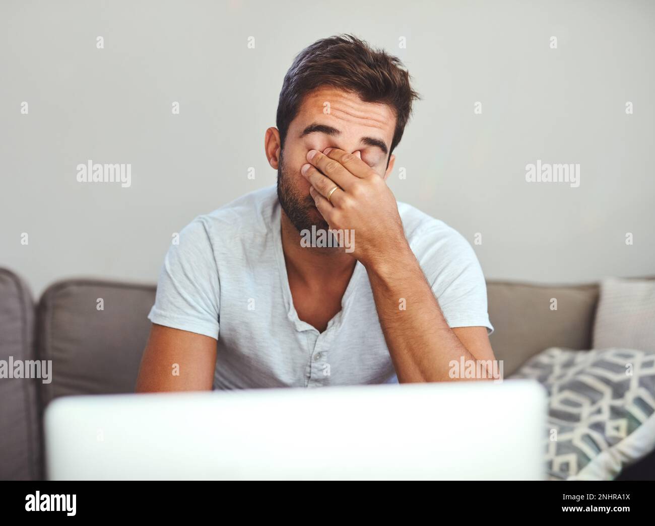 Ressentir la tension. un beau jeune homme qui regarde stressé en  travaillant sur son ordinateur portable à la maison Photo Stock - Alamy