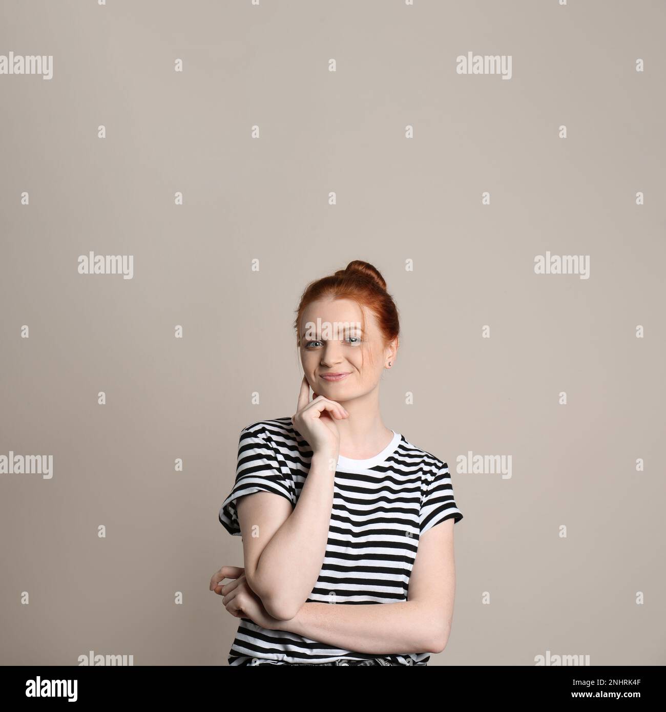 Portrait franc de la femme heureuse aux cheveux rouges avec un sourire charmant sur fond beige Banque D'Images