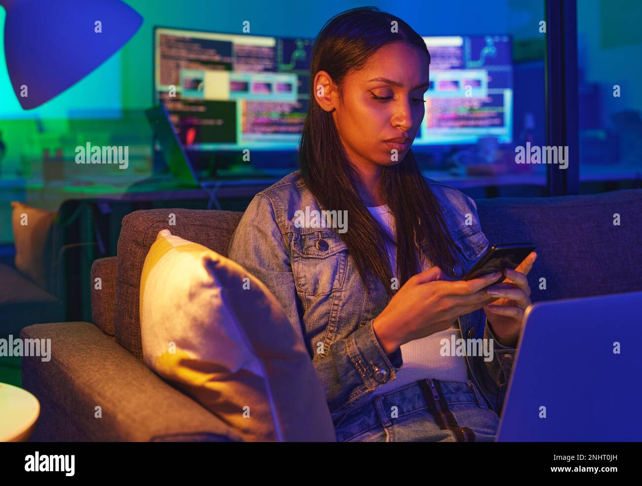 Téléphone, dactylographie et triste femme à la maison sur les médias sociaux, SMS ou navigation sur Internet dans la lumière du néon. Nuit, technologie et femme programmeur sur le canapé avec Banque D'Images