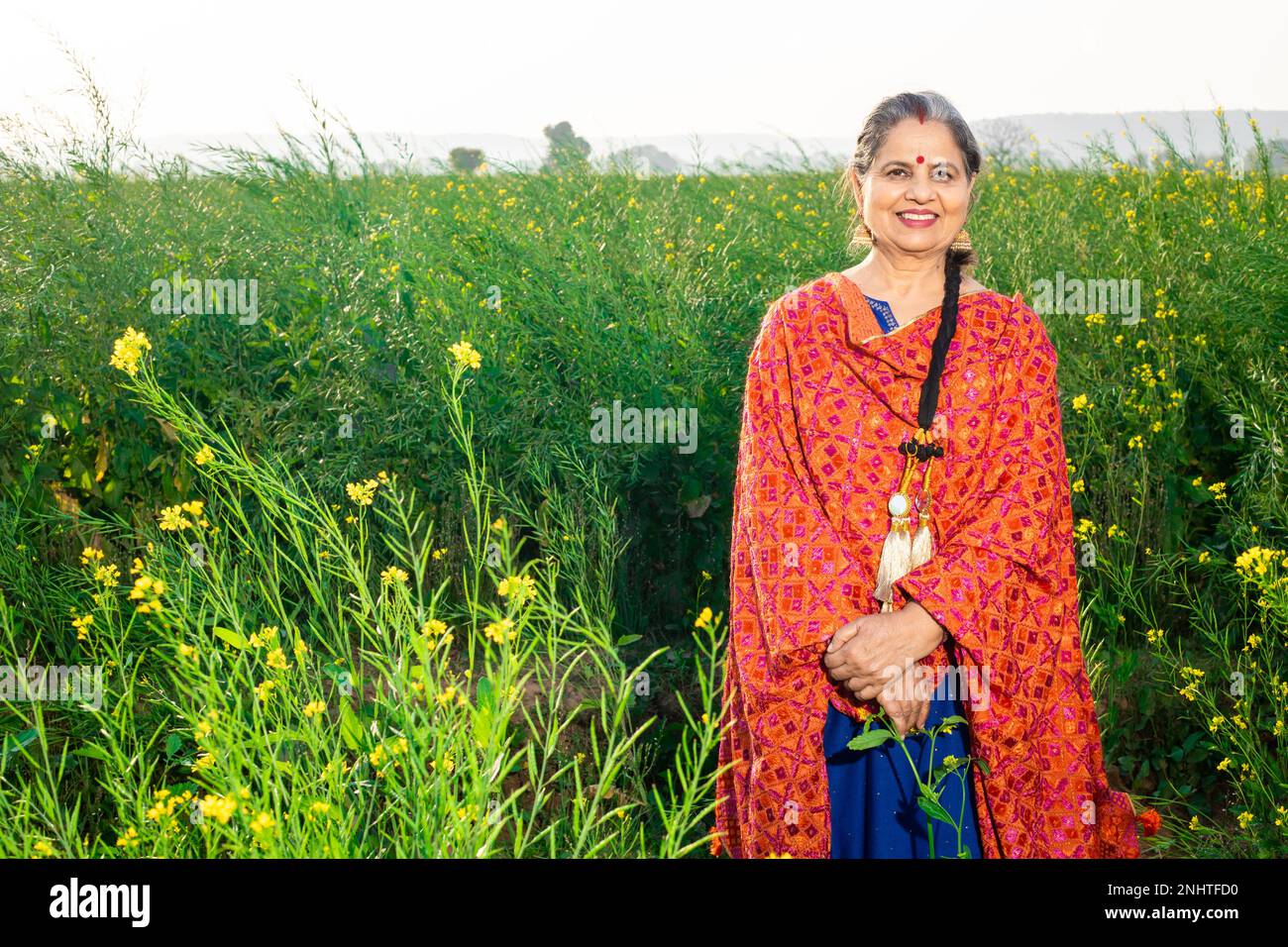 Portrait d'une femme pendjabi haute heureuse portant une tenue traditionnelle colorée debout sur le terrain de l'agriculture. Banque D'Images