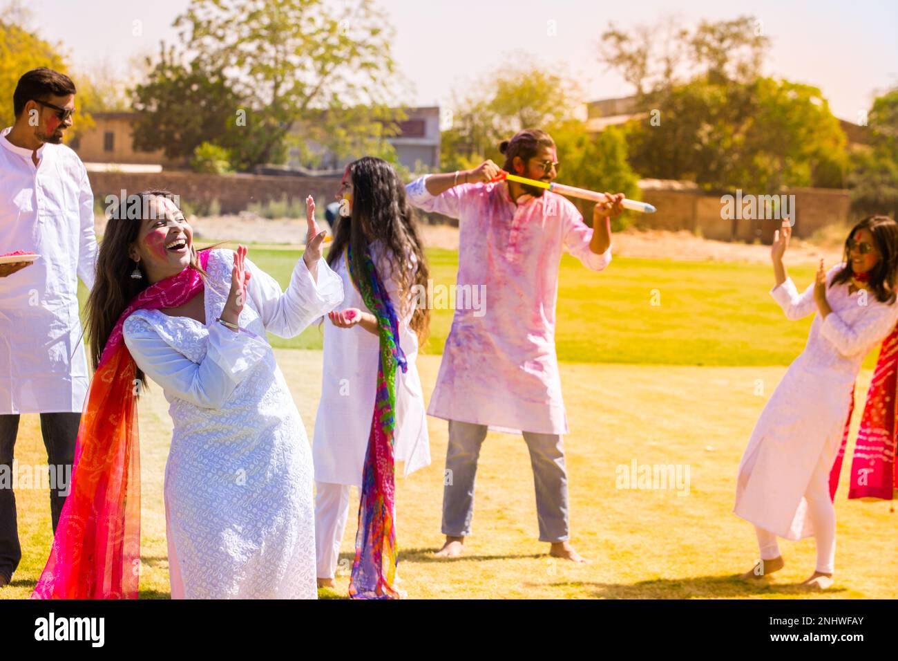 Jeunes indiens heureux portant une tenue de kurta blanche célébrant le festival holi avec poudre colorée ou gulal au parc extérieur. Banque D'Images