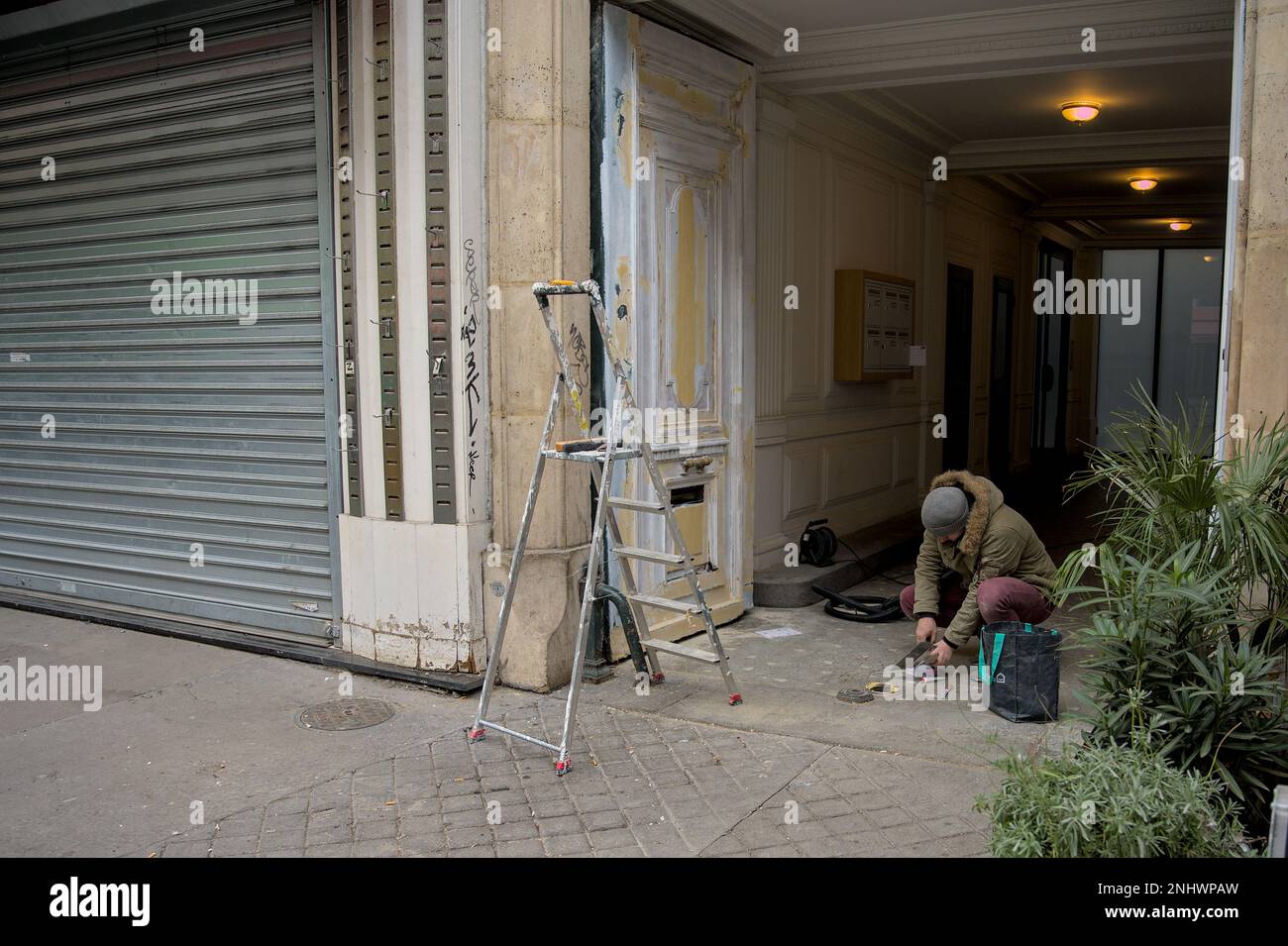 Un homme de main qui fixe une porte dans les rues de Paris Banque D'Images
