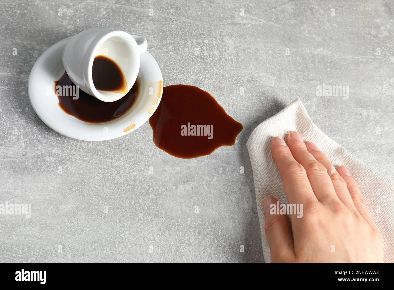 Femme essuyant du café renversé sur une table grise, gros plan Banque D'Images