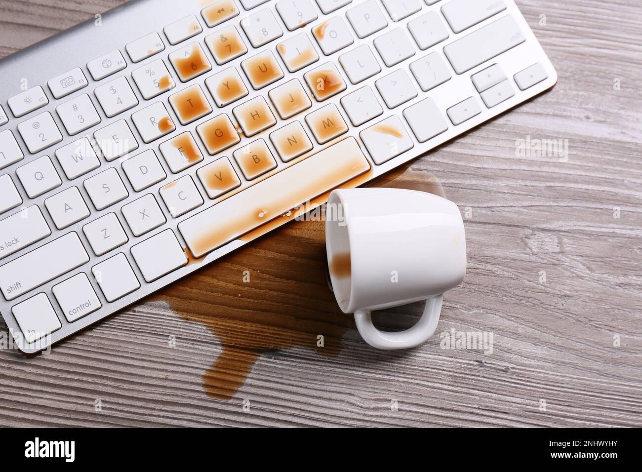 Tasse de café renversé sur le clavier de l'ordinateur sur une table en bois, plat Banque D'Images Tasse de café renversé sur le clavier de l'ordinateur sur une table en bois, plat Banque D'Images
