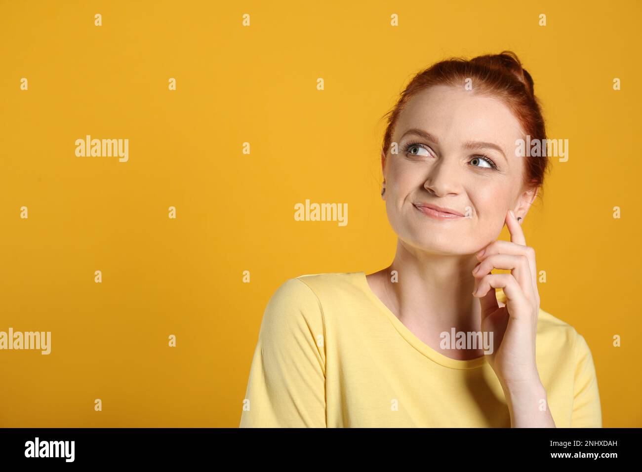 Portrait de la femme heureuse aux cheveux rouges sur fond jaune, espace pour le texte Banque D'Images