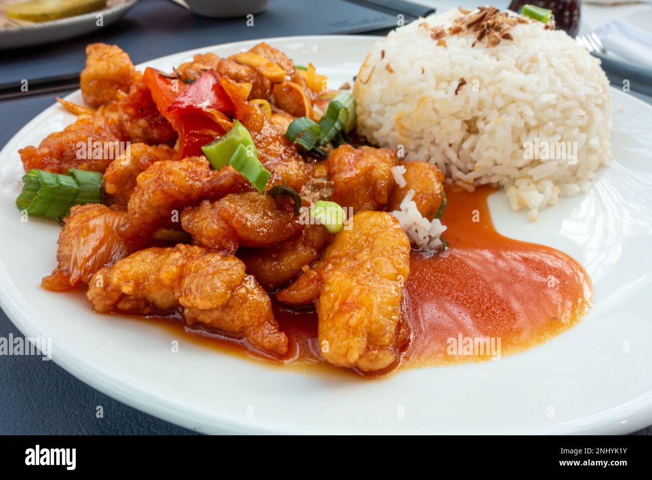 Une assiette de poulet aigre-doux avec du riz bouilli, une cuisine d'inspiration chinoise servie dans une aire de restauration britannique. Banque D'Images Une assiette de poulet aigre-doux avec du riz bouilli, une cuisine d'inspiration chinoise servie dans une aire de restauration britannique. Banque D'Images