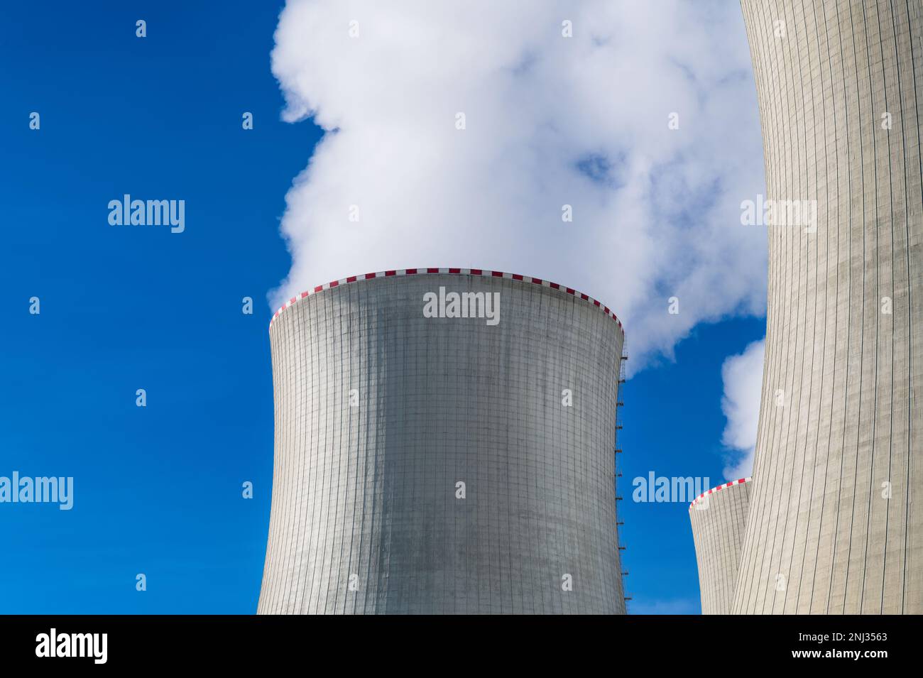 Gros plan de la centrale électrique des tours de refroidissement avec des nuages blancs de vapeur sur fond bleu ciel. Cheminées de grande taille dans une centrale nucléaire. Crise énergétique. Banque D'Images