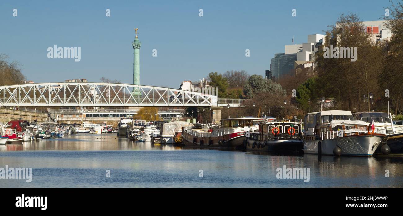 Maison Bateaux amarrés dans le Canal Saint Martin et le bassin de l'Arsenal avec la Passerelle de Mornay et juillet colonne en arrière-plan, Paris Banque D'Images