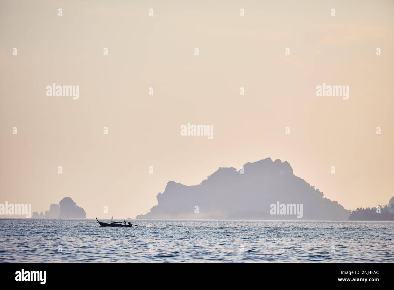 Longue queue traditionnelle en silhouette près des îles tropicales au coucher du soleil dans la mer d'Andaman, sud de la Thaïlande Banque D'Images