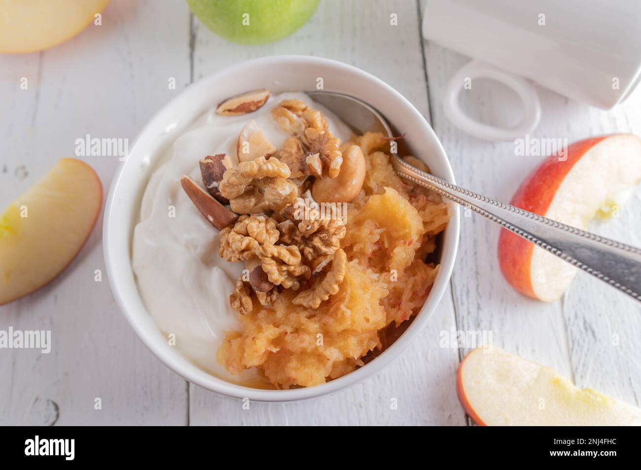 Bol à petit déjeuner sans grain avec yaourt grec, pommes râpées, noix et noix du brésil sur fond blanc Banque D'Images