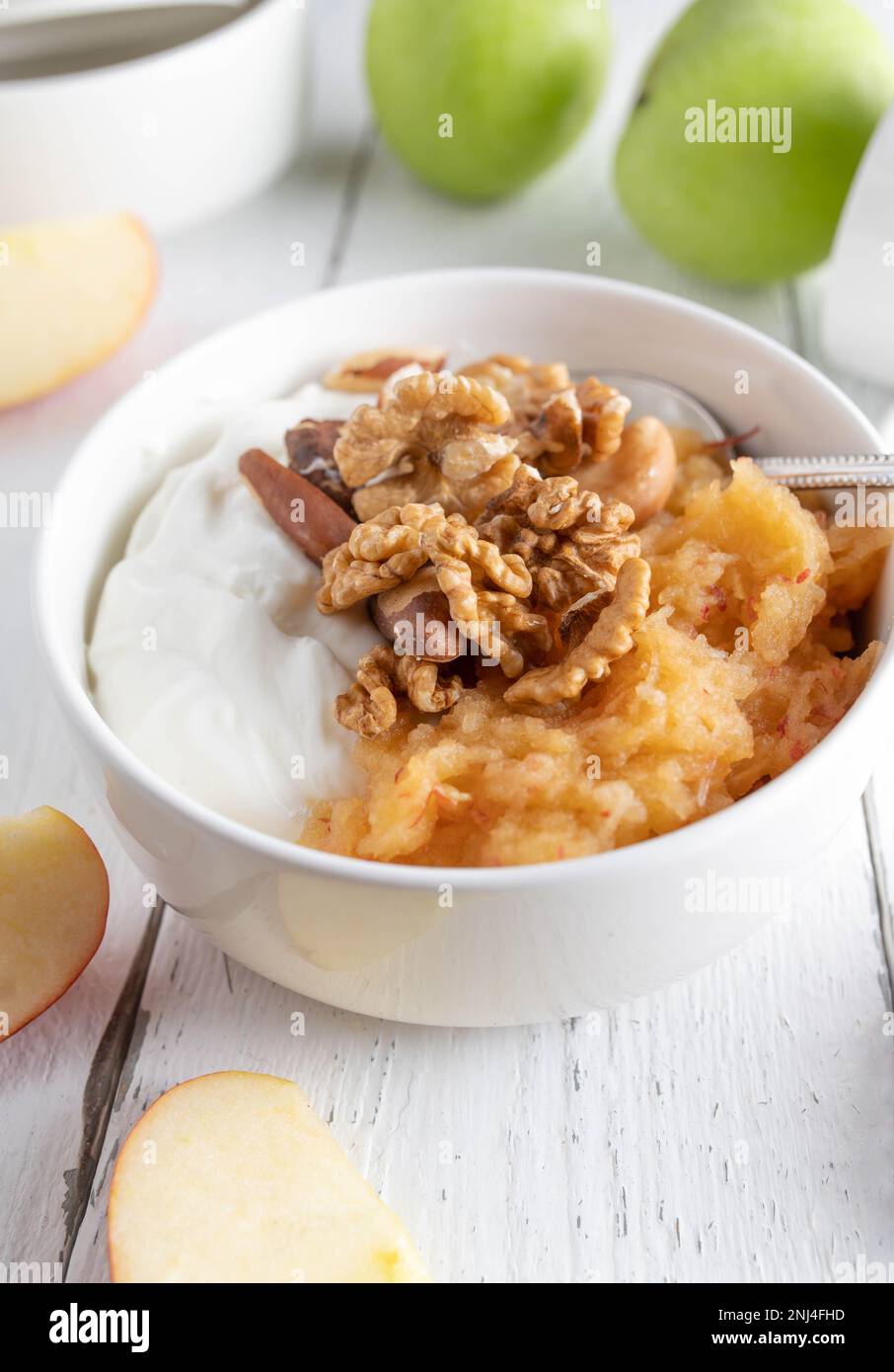 Bol de petit déjeuner sans céréales ni gluten avec yaourt grec, pommes râpées et noix sur fond blanc Banque D'Images