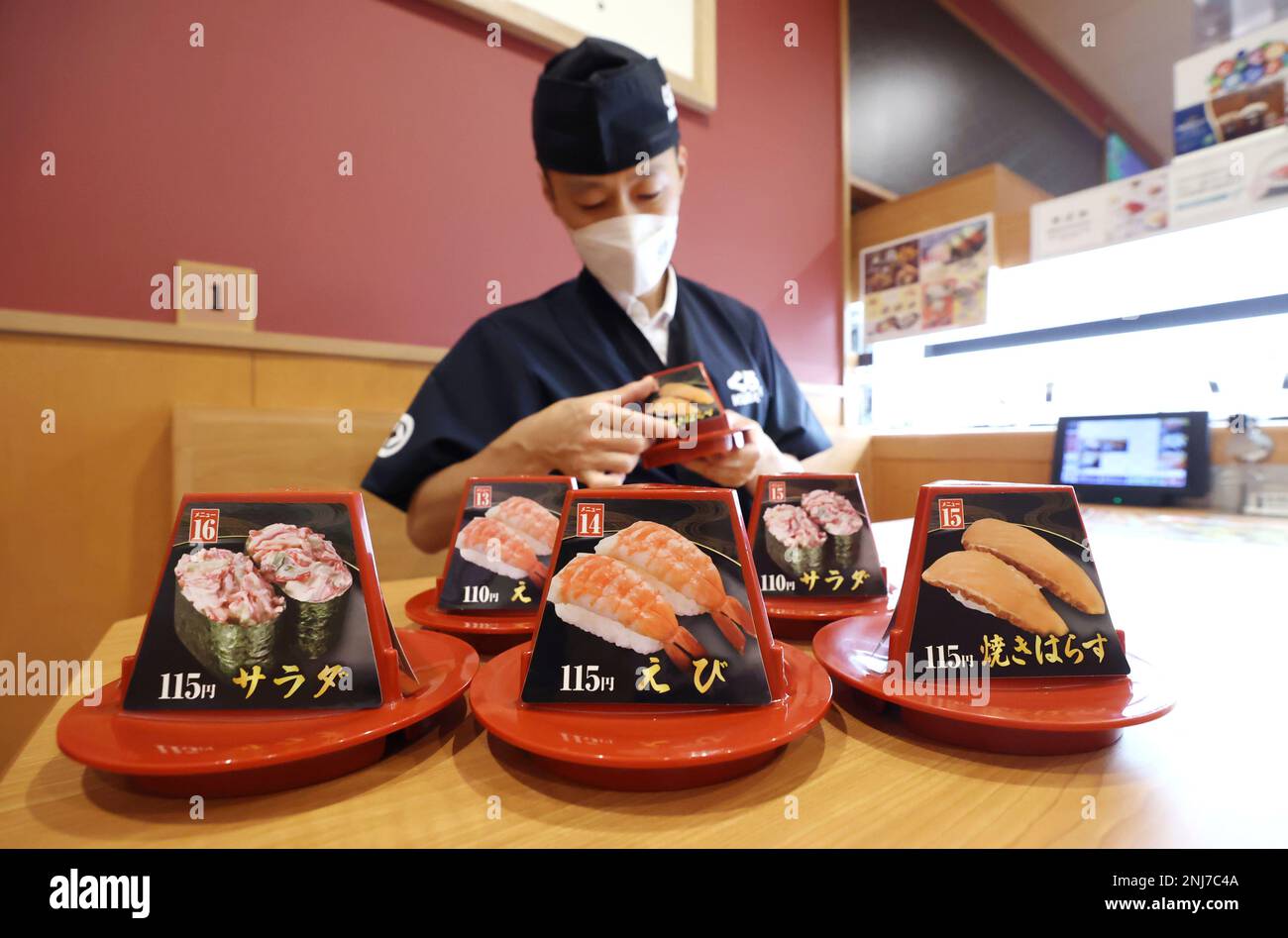 An employee changes the price tag from 110 yen to 115 yen due to the