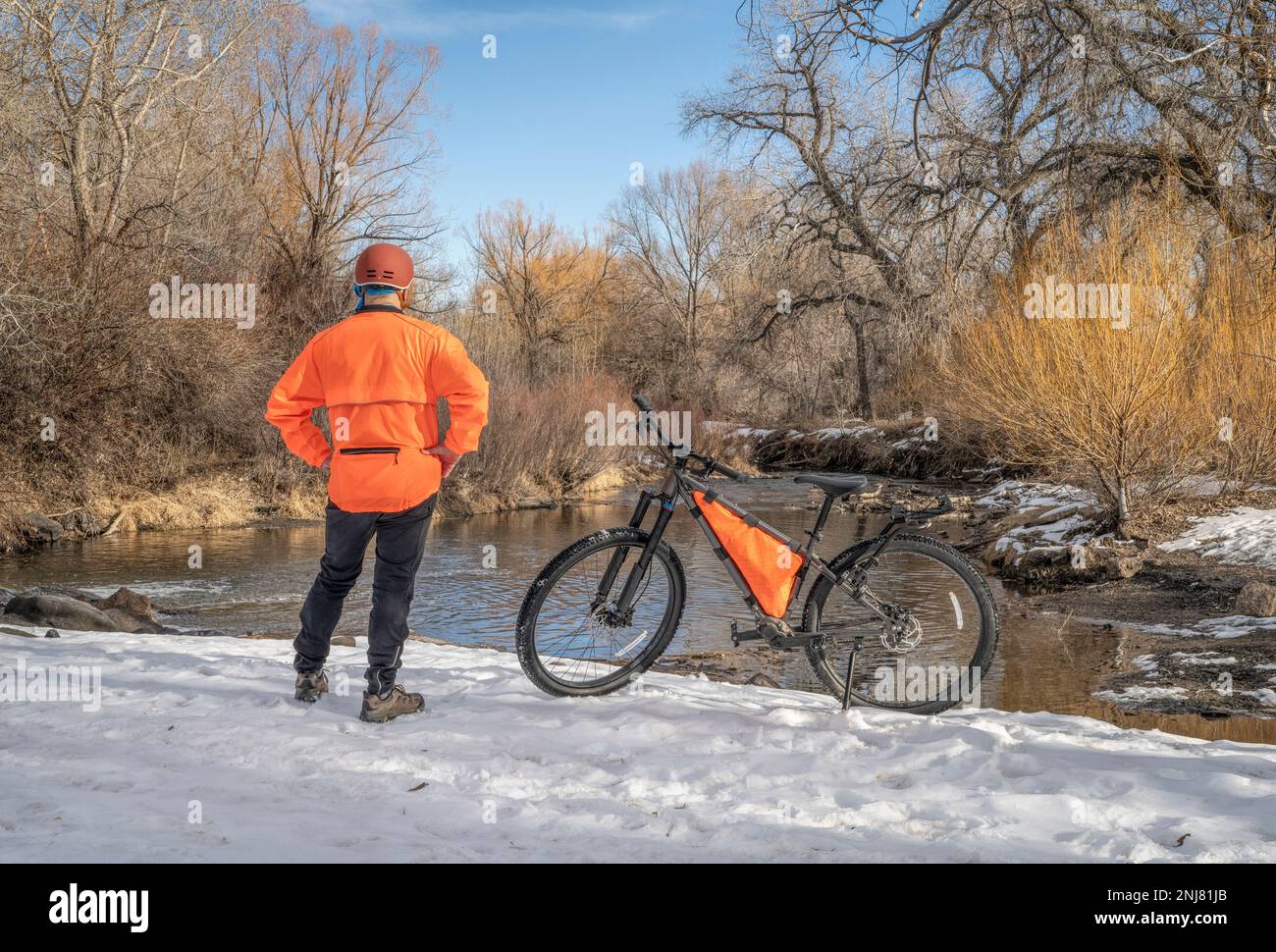 Cycliste mature avec un vélo de montagne sur le rivage d'une rivière en hiver - Big Thompson River à Loveland, Colorado Banque D'Images