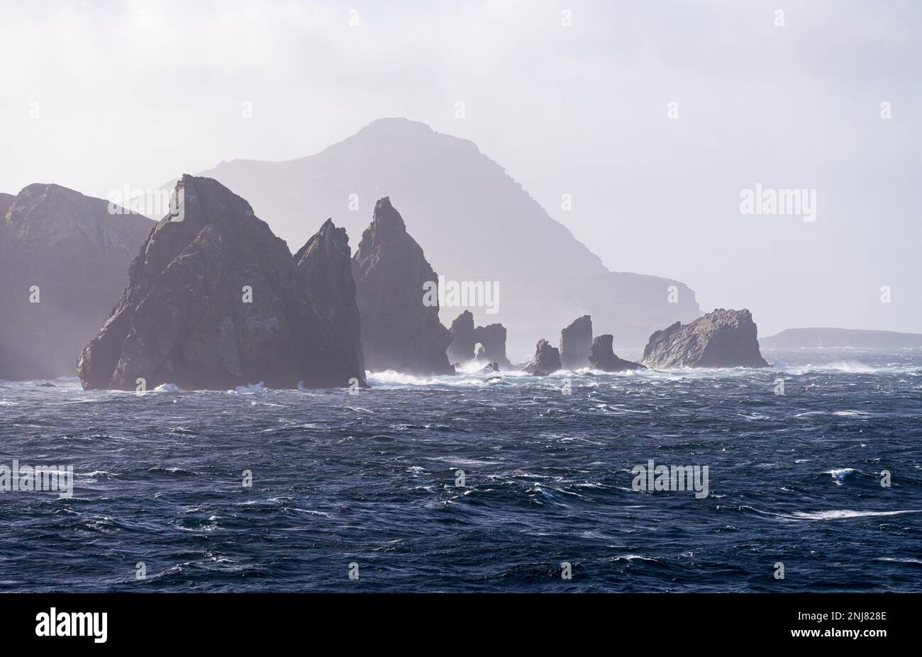 Escarpages rocheuses dentelées au large de l'île Hornos avec Cape Horn à distance Banque D'Images