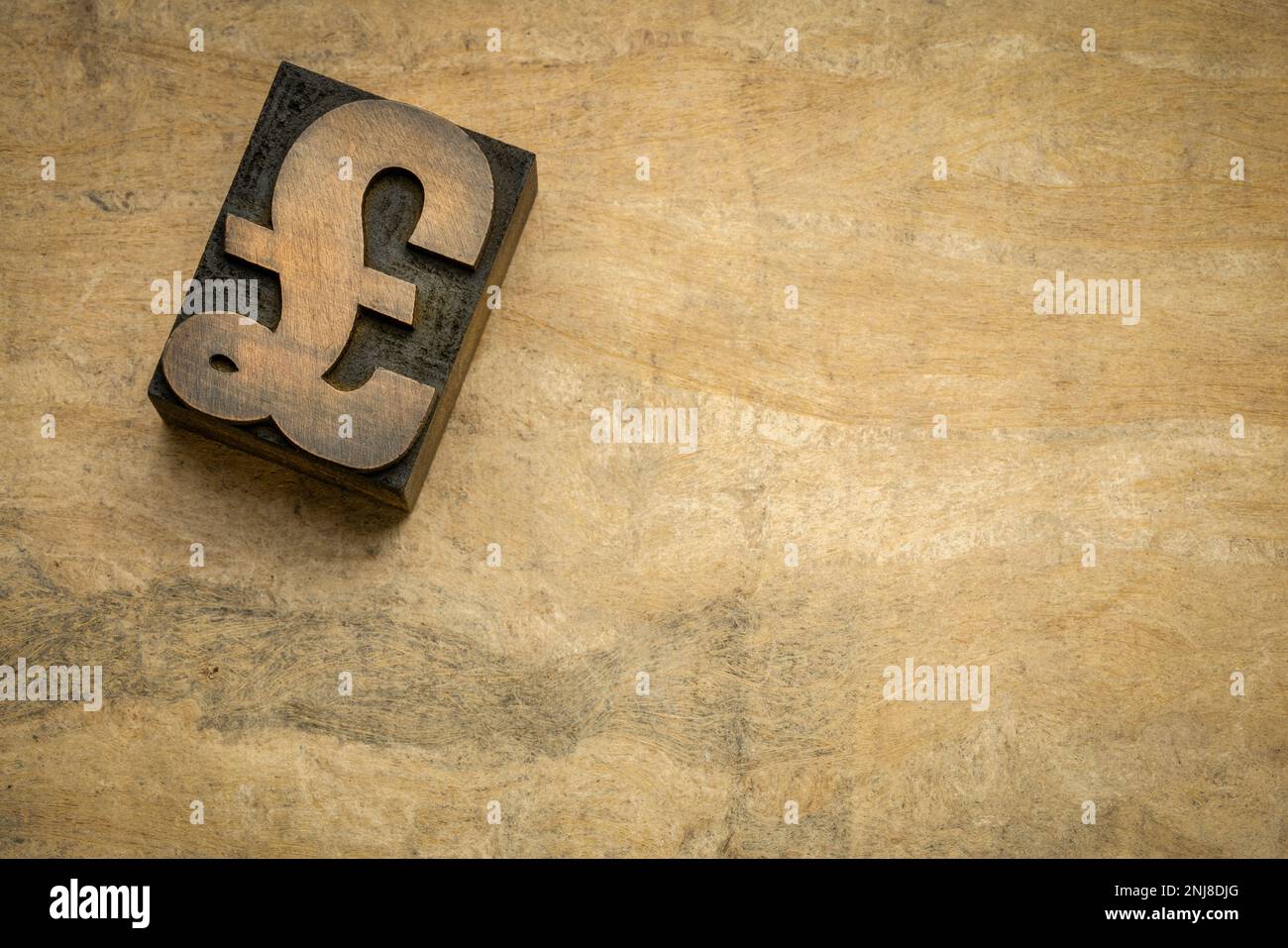 Le symbole livre sterling britannique en forme de bloc d'impression de type bois de typographie contre du papier artisanal en écorce avec un espace de copie Banque D'Images