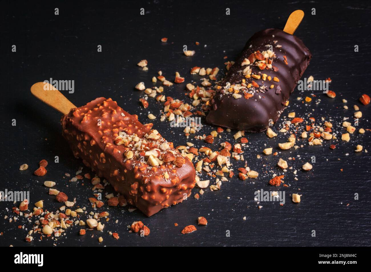 Le gâteau au chocolat apparaît avec des noix sous forme de popsicle sur le bâton sur fond de tableau noir d'ardoise Banque D'Images