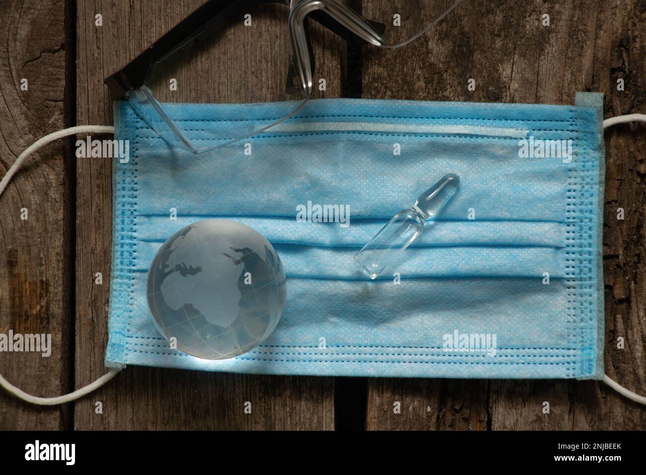 globe en verre et ampoule avec des lunettes de médicaments et de médecin sur un masque médical sur une table Banque D'Images