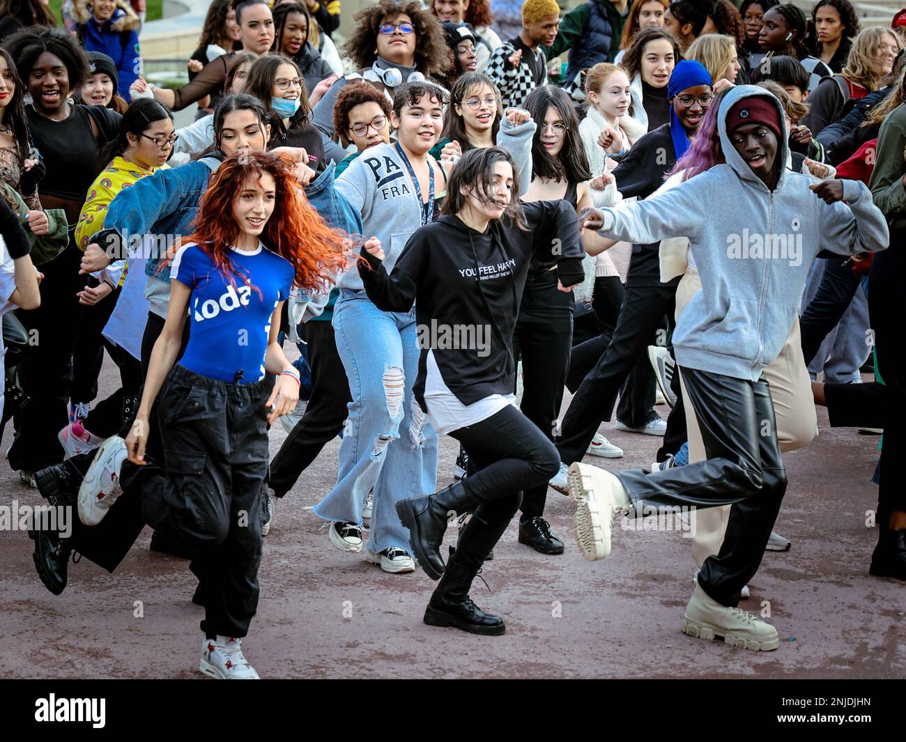 Un groupe diversifié de jeunes danseurs participent à une joyeuse performance flash mob, remplissant la rue de mouvement, d'énergie et d'unité Banque D'Images