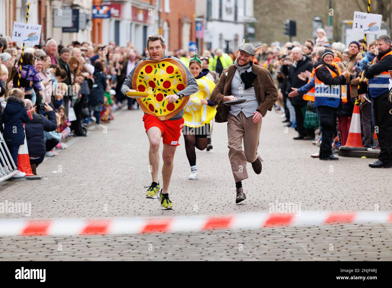 La course annuelle de crêpes Shrove Tuesday s'est tenue à Lichfield, Staffordshire, en Angleterre. L'événement comprend des courses pour enfants, une course de mascotte et des courses pour hommes et femmes. L'événement commence à midi et est accompagné par le crieur de la ville et jugé par le Seigneur Maire. Photo à gauche, portant une crêpe, vainqueur de l'événement de mascotte Austin Brauser du club de course WIP. Banque D'Images