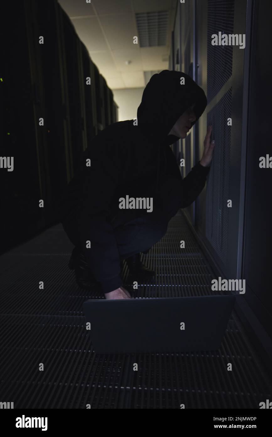 Piratage informatique, salle de serveurs et personne sur ordinateur portable pour le codage de logiciels, la criminalité dans les centres de données et la cyberpunk dans l'obscurité. Pirate réseau, femme ou utilisateur en cybersécurité Banque D'Images
