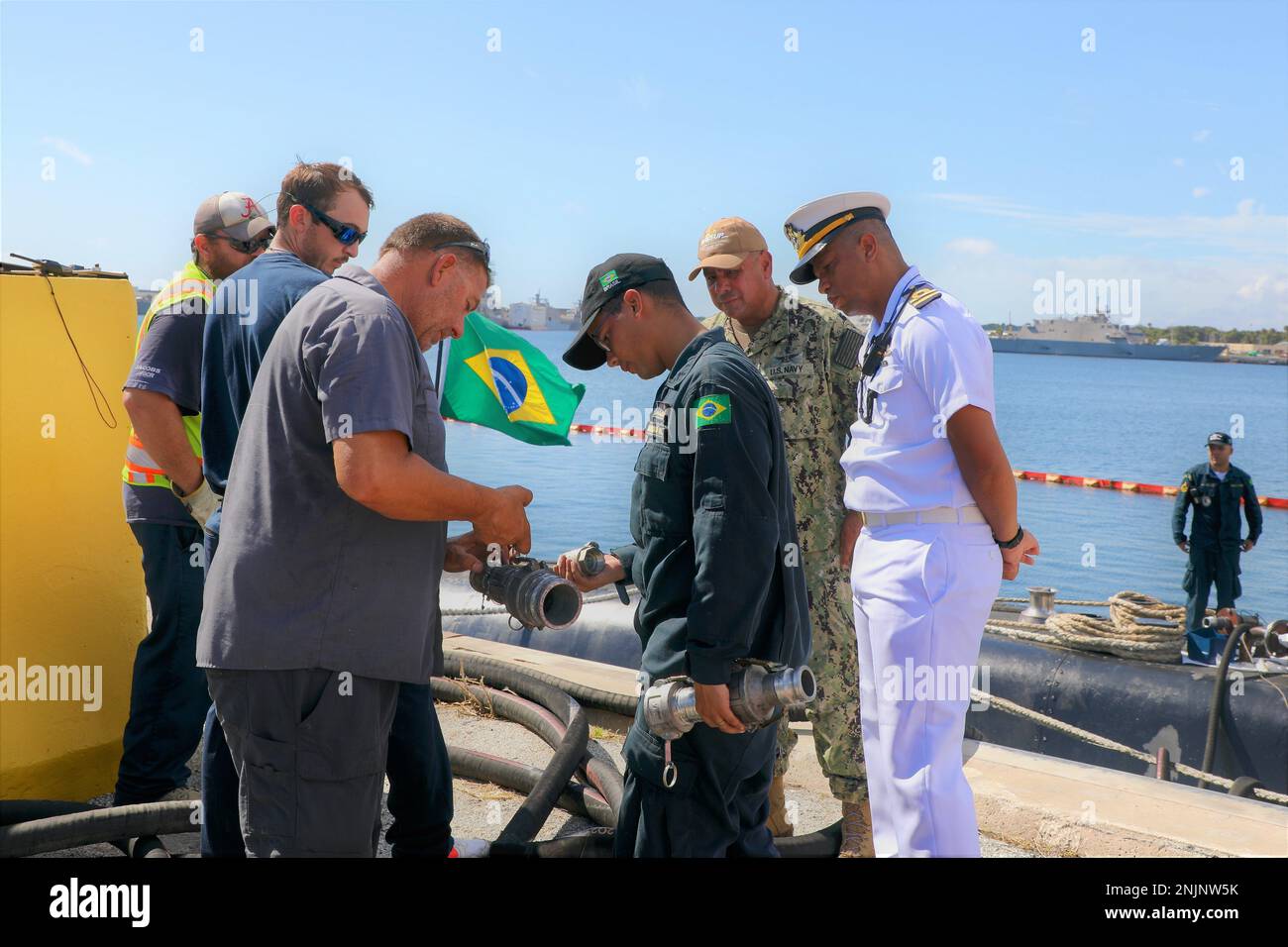 ÉTATS-UNIS Navy Logistics Specialist 1st Class Luis Martinez, deuxième à partir de la droite, aide à faciliter la communication entre les membres d'équipage brésiliens Gabriel Fontes Melo Bitencort, centre, Nelson Luiz Moreira Da Silva Jr., à droite, et les employés de la compagnie de carburant civile des États-Unis, à gauche. Banque D'Images