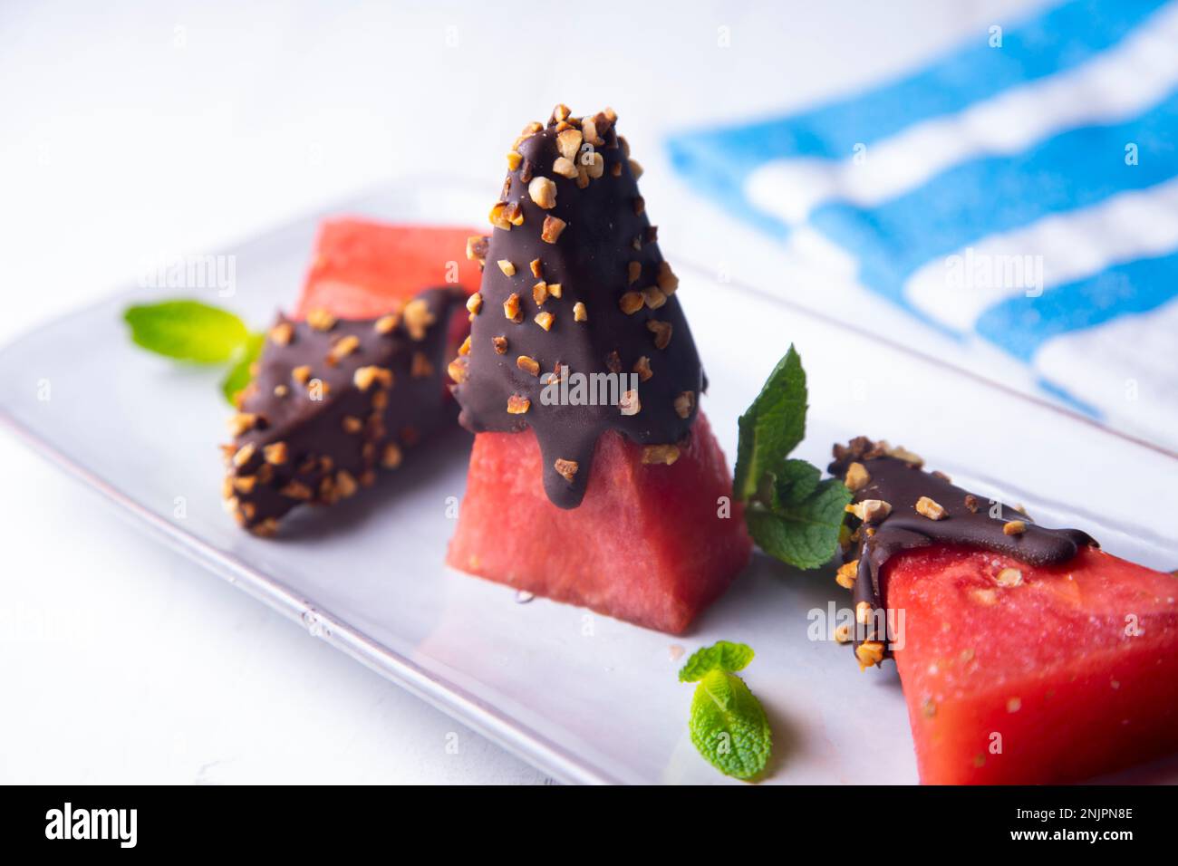 Morceaux de pastèque fraîche trempée dans du chocolat et recouverte d'amandes caramélisées. Banque D'Images