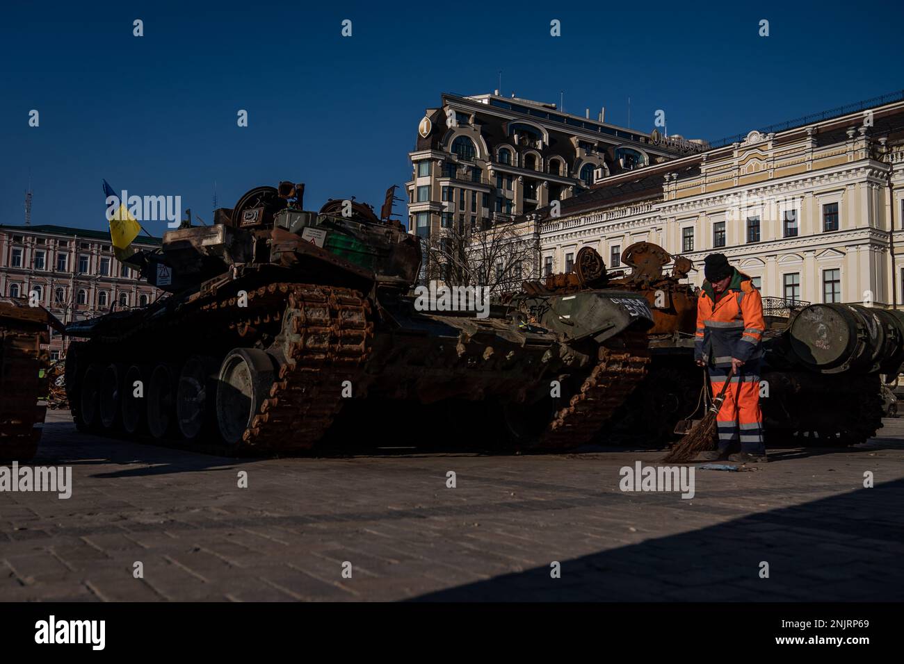 Un employé de la ville nettoie autour de l'exposition d'équipements militaires russes détruits, l'exposition en plein air sur la place Mykhailivska à Kiev, avant le premier anniversaire vendredi de l'invasion russe de l'Ukraine. Date de la photo: Jeudi 23 février 2023. Banque D'Images