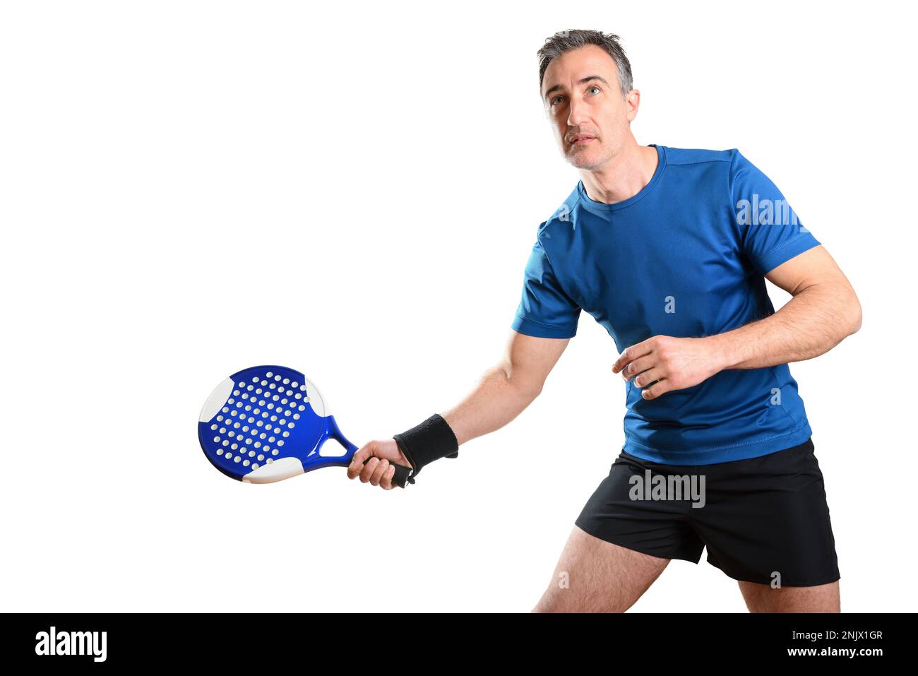 Portrait d'un homme jouant au paddle-tennis avec une raquette en main pour recevoir une balle portant une tenue de sport bleue et noire et un sac isolé blanc Banque D'Images