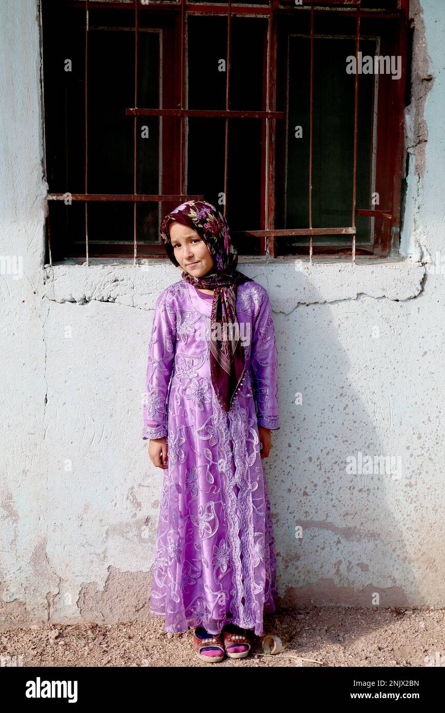 OVAKENT,HATAY,TURQUIE-DÉCEMBRE 10:fille afghane non identifiée avec une robe traditionnelle debout près du mur. 10 décembre, 2016, Ovakent, Hatay, Turquie Banque D'Images
