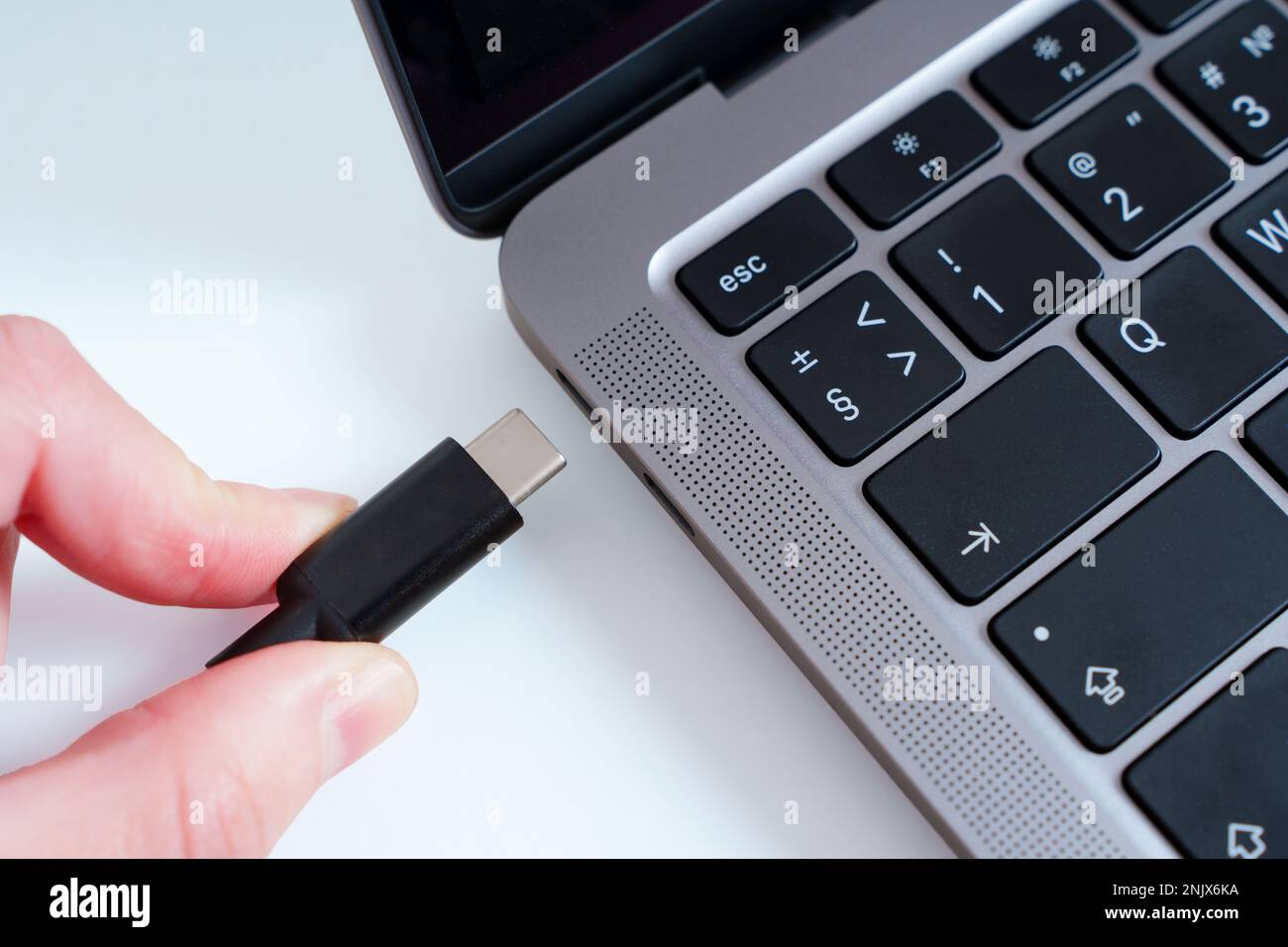 Vue rapprochée d'une main connectant un câble USB de type C à un ordinateur portable isolé. Concept moderne de port pratique. Banque D'Images