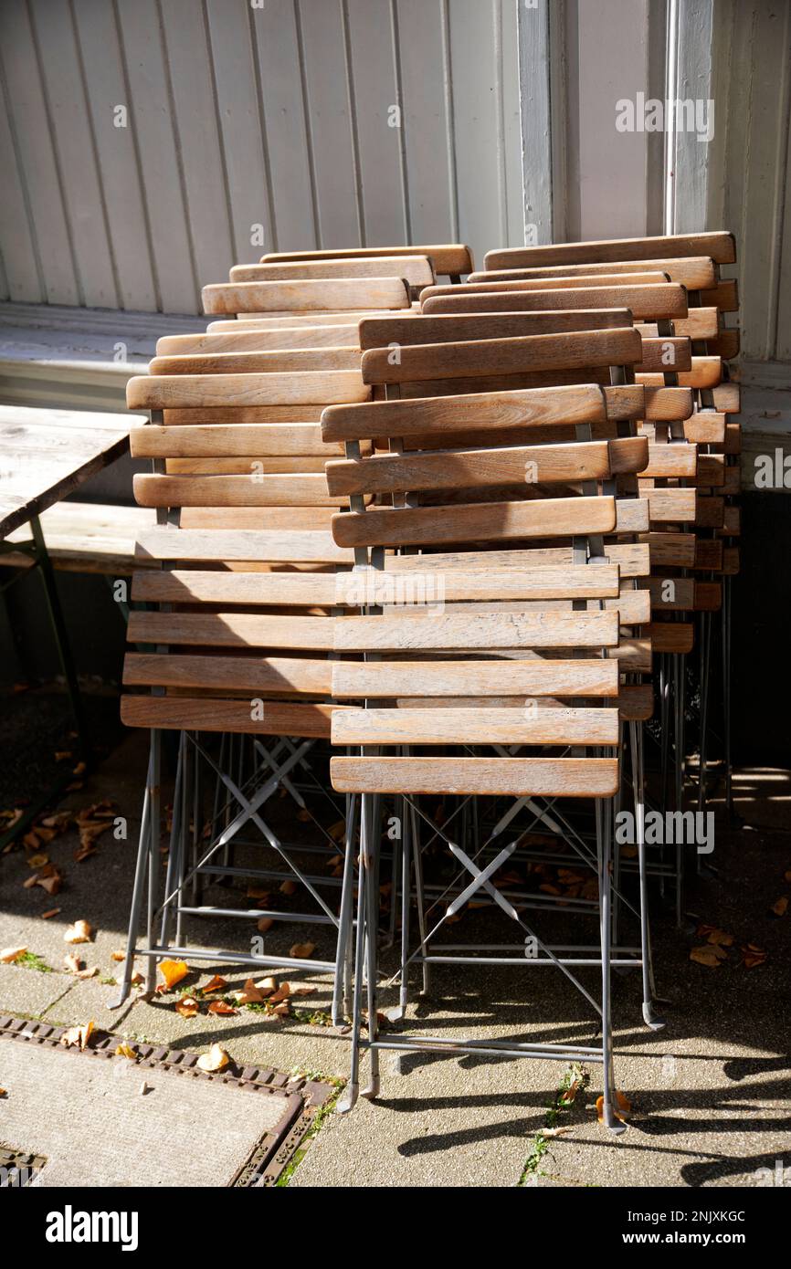 Zusammengeklapte Holzstühle im Aussengsastreubereich in der Altstadt Hattingen. Sie werden von der sonne beschienen. Banque D'Images