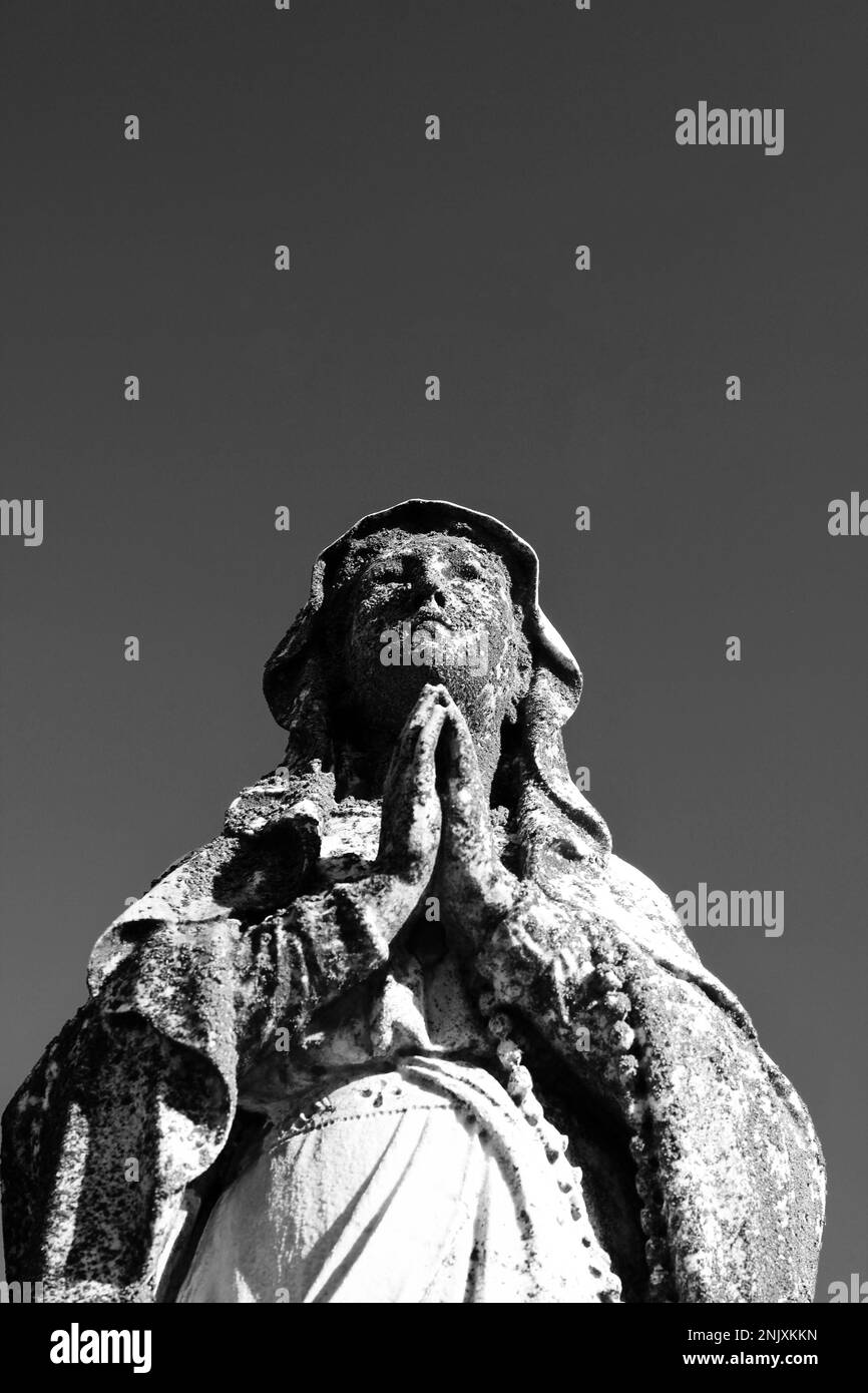 Une statue en pierre naturelle usée et abîmée de la Vierge Marie tenant ...