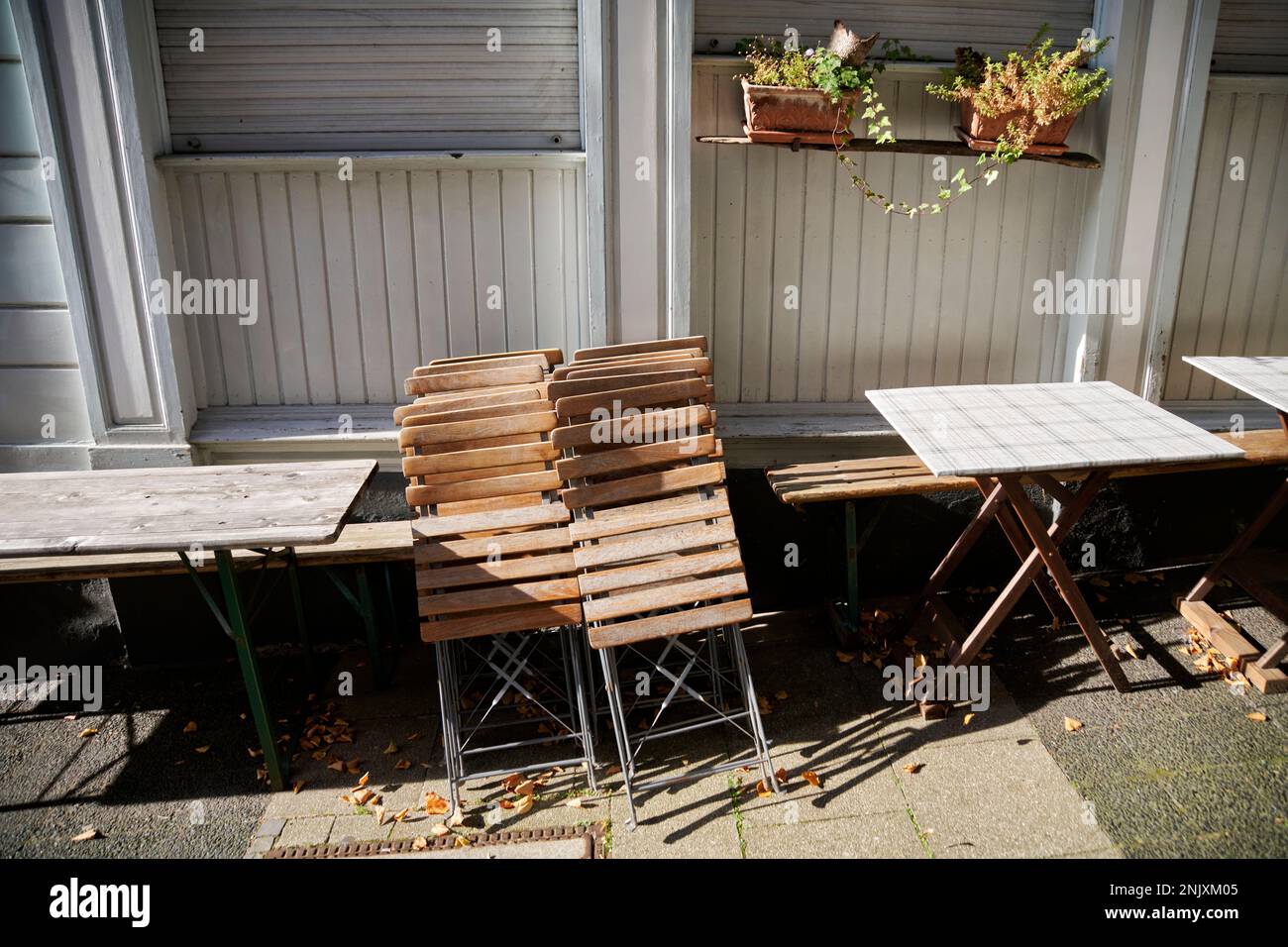 Zusammengeklapte Holzstühle im Aussengsastreubereich in der Altstadt Hattingen. Sie werden von der sonne beschienen. Banque D'Images