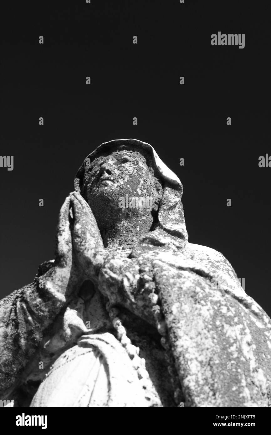 Une statue en pierre naturelle usée et abîmée de la Vierge Marie tenant ...
