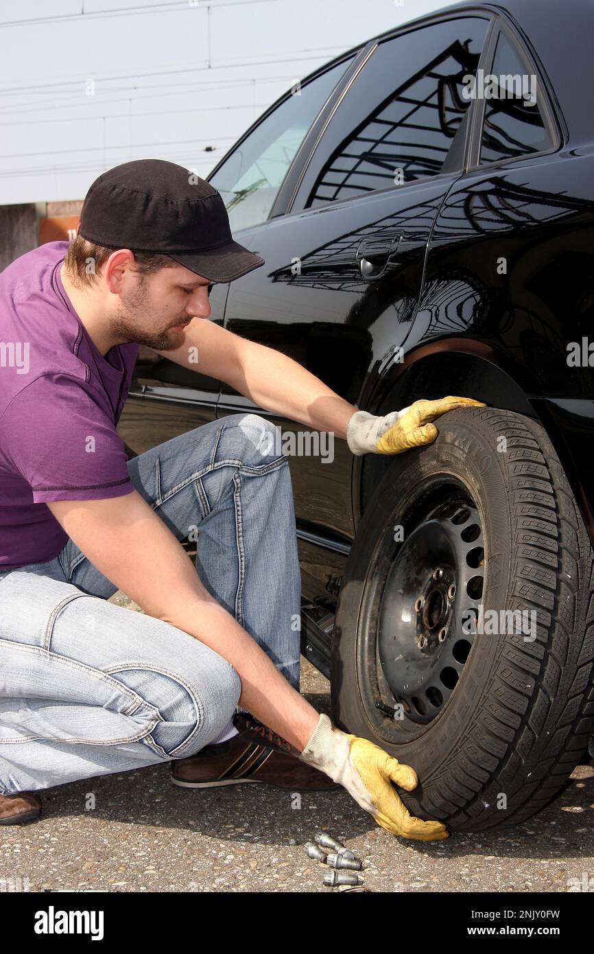 changement de pneu, jeune homme change les pneus sommer en pneus d'hiver, image de série 5/13 Banque D'Images