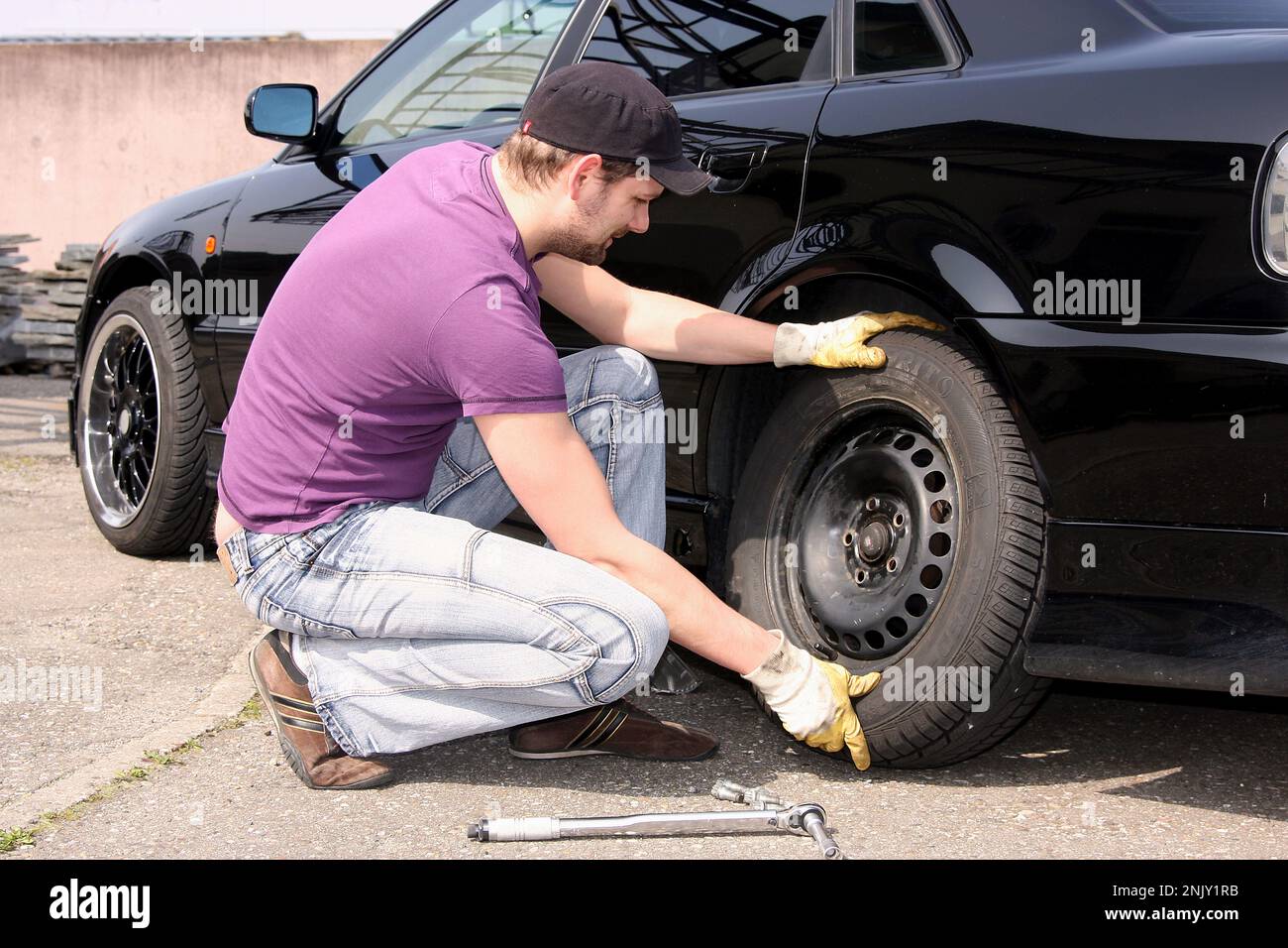 changement de pneu, jeune homme change les pneus sommer en pneus d'hiver, image de série 6/13 Banque D'Images